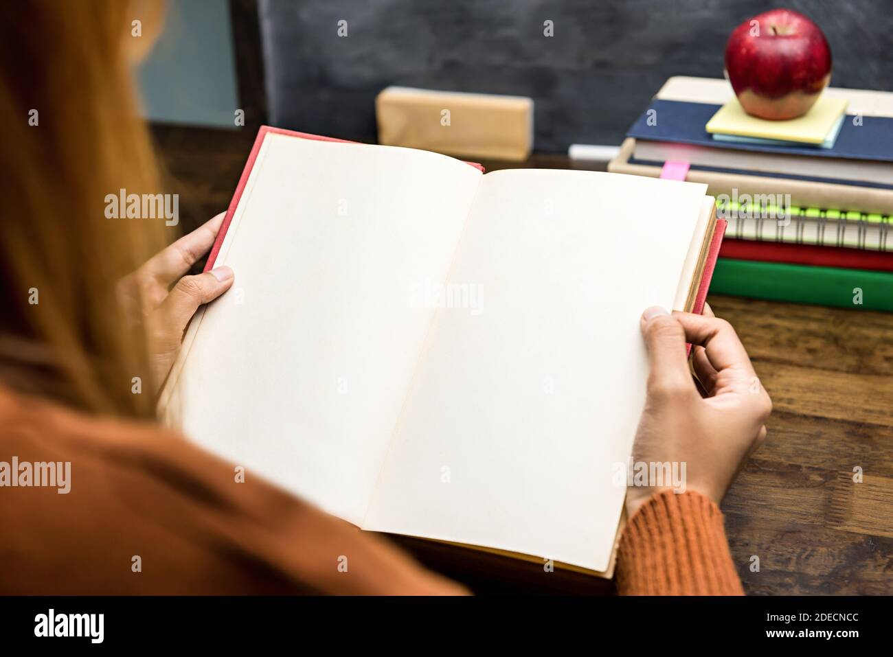 Giovane studentessa che legge il libro al tavolo in classe preparazione per un test a scuola Foto Stock