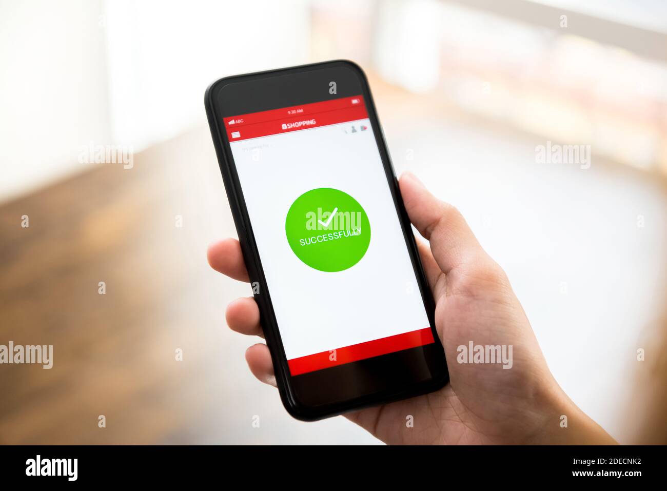 Il segno di conferma dell'acquisto online viene visualizzato nella schermata dell'applicazione per smartphone dopo aver effettuato il pagamento digitale da parte di una donna cliente Foto Stock