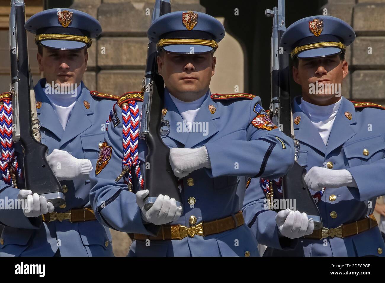 Tre voci della Guardia del Castello di Praga nelle loro uniformi estive blu pallido che marciano verso lo spettatore con fucili a spalla con baionette fissate durante una cerimonia del Cambio della Guardia nel primo cortile del castello. Le perniciane alle porte del castello medievale cambiano ora e c'è anche un giorno 12 ore cerimonia di cambio della Guardia, tra cui un fanfare e una cerimonia bandiera. Il castello è la residenza ufficiale e l'ufficio del presidente della Repubblica Ceca o Czechia. Foto Stock