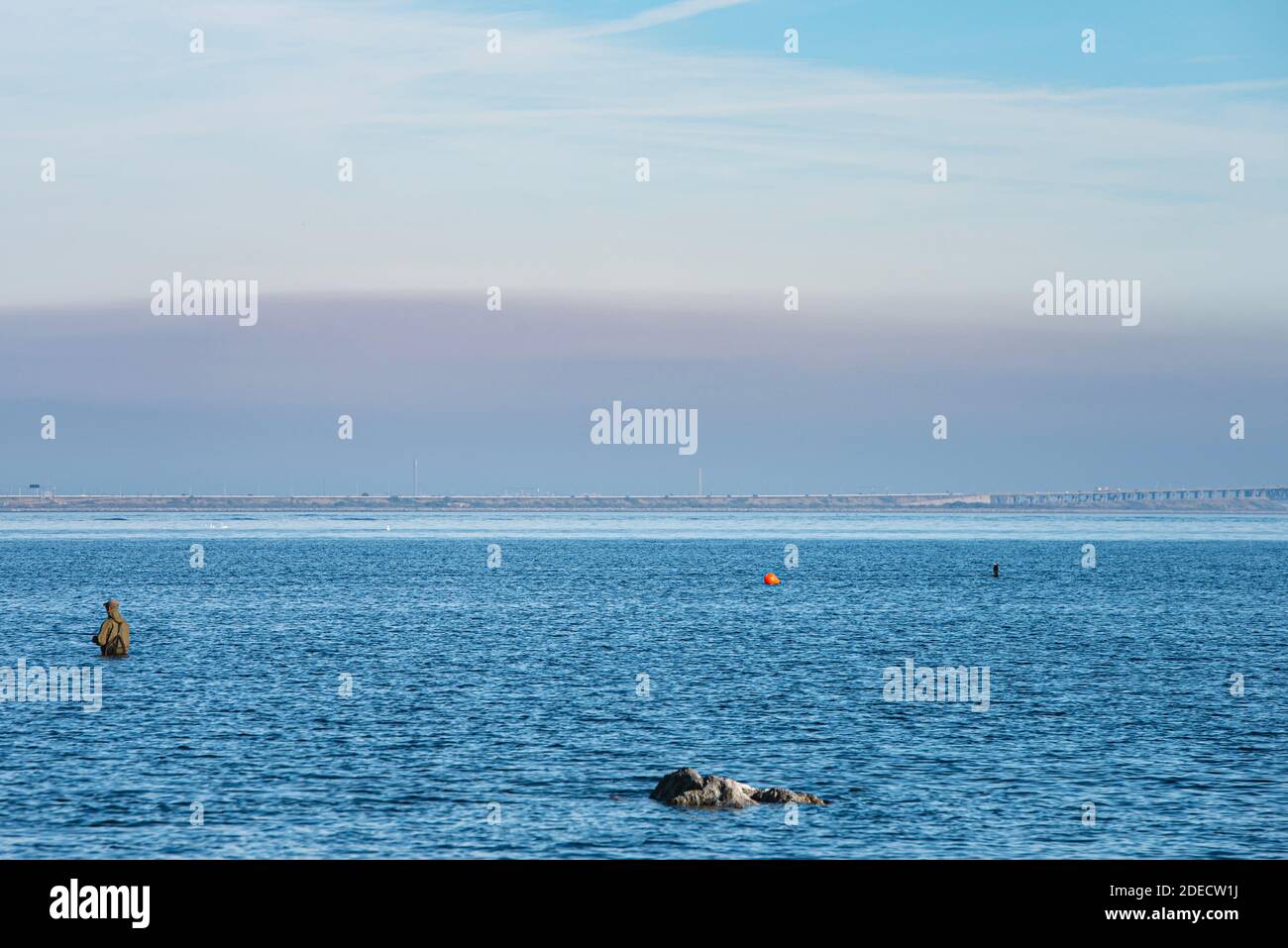 Un pescatore solista con attrezzi isolanti è parzialmente sommerso in mare con lo scopo di una buona cattura di pesce o di pesca nello stretto di Oresund, Mar Baltico Foto Stock