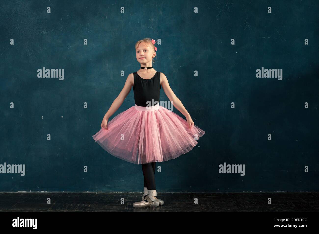 Bambina caucasica in tutu rosa e scarpe pointe allenamento ballet posizione contro il muro in studio Foto Stock