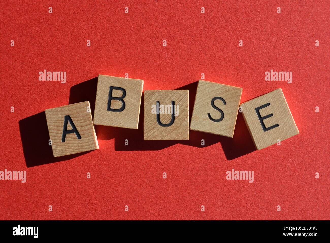 Abuso, parola in lettere alfabetiche in legno isolato su sfondo rosso Foto Stock