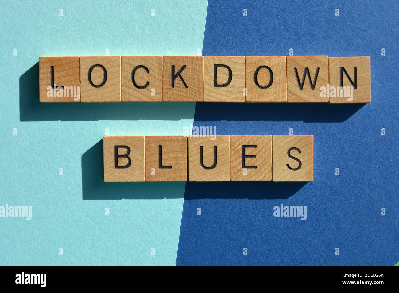 Lockdown Blues, parole in lettere alfabetiche in legno isolate su sfondo blu. Foto Stock