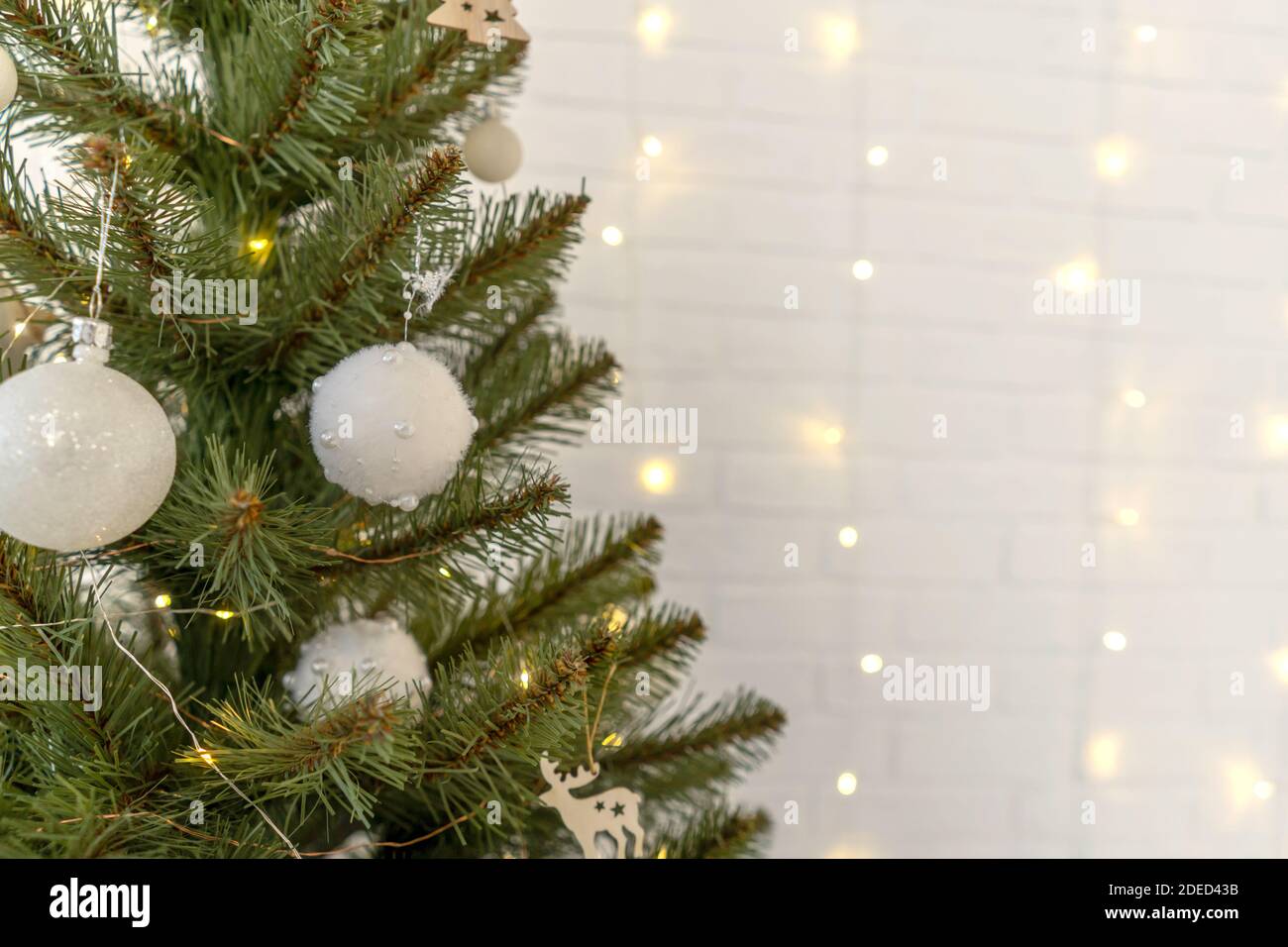 Parte dell'albero di Natale con palline bianche, ghirlande di luci di  Natale su muro bianco di mattoni su sfondo. Spazio di copia Foto stock -  Alamy