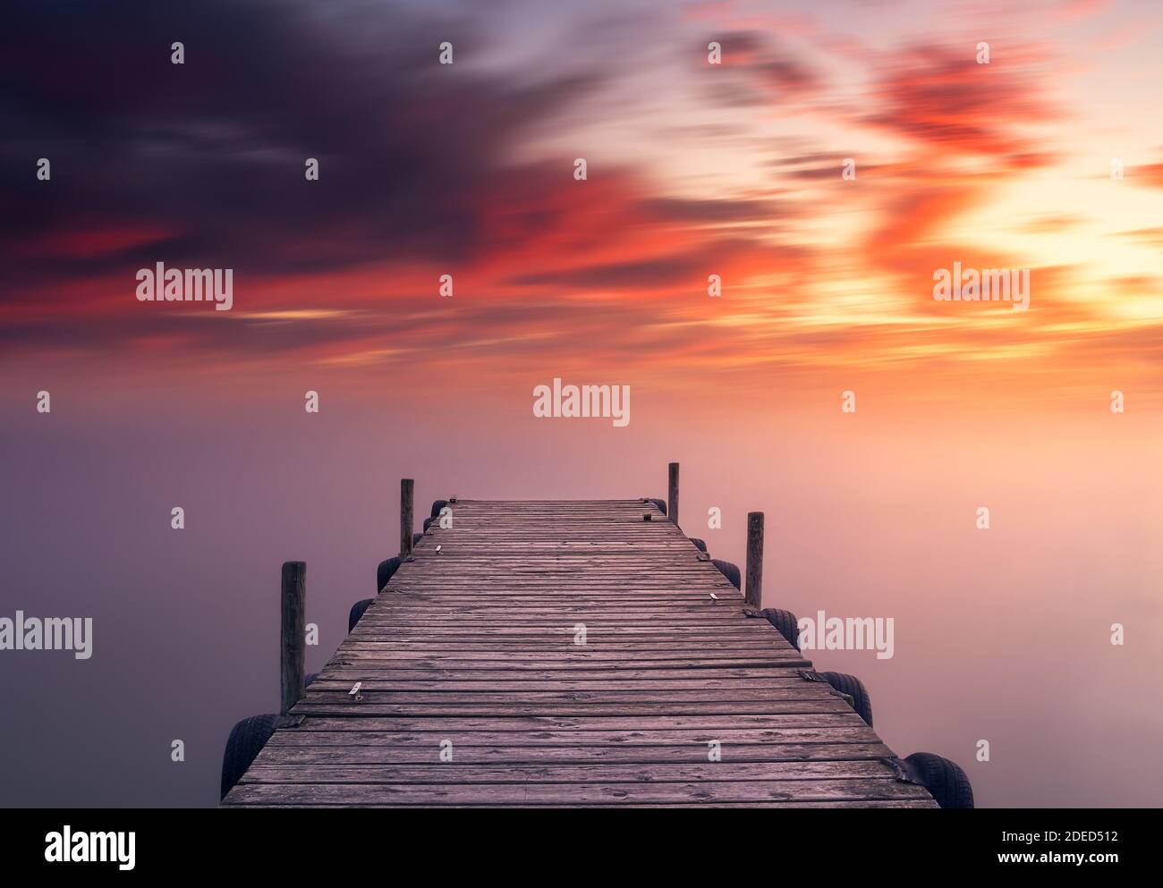 Rilassante e bellissimo tramonto rosso mediterraneo, sul lago di Albufera a Valencia, in Spagna, su un molo di fronte a acque setose Foto Stock