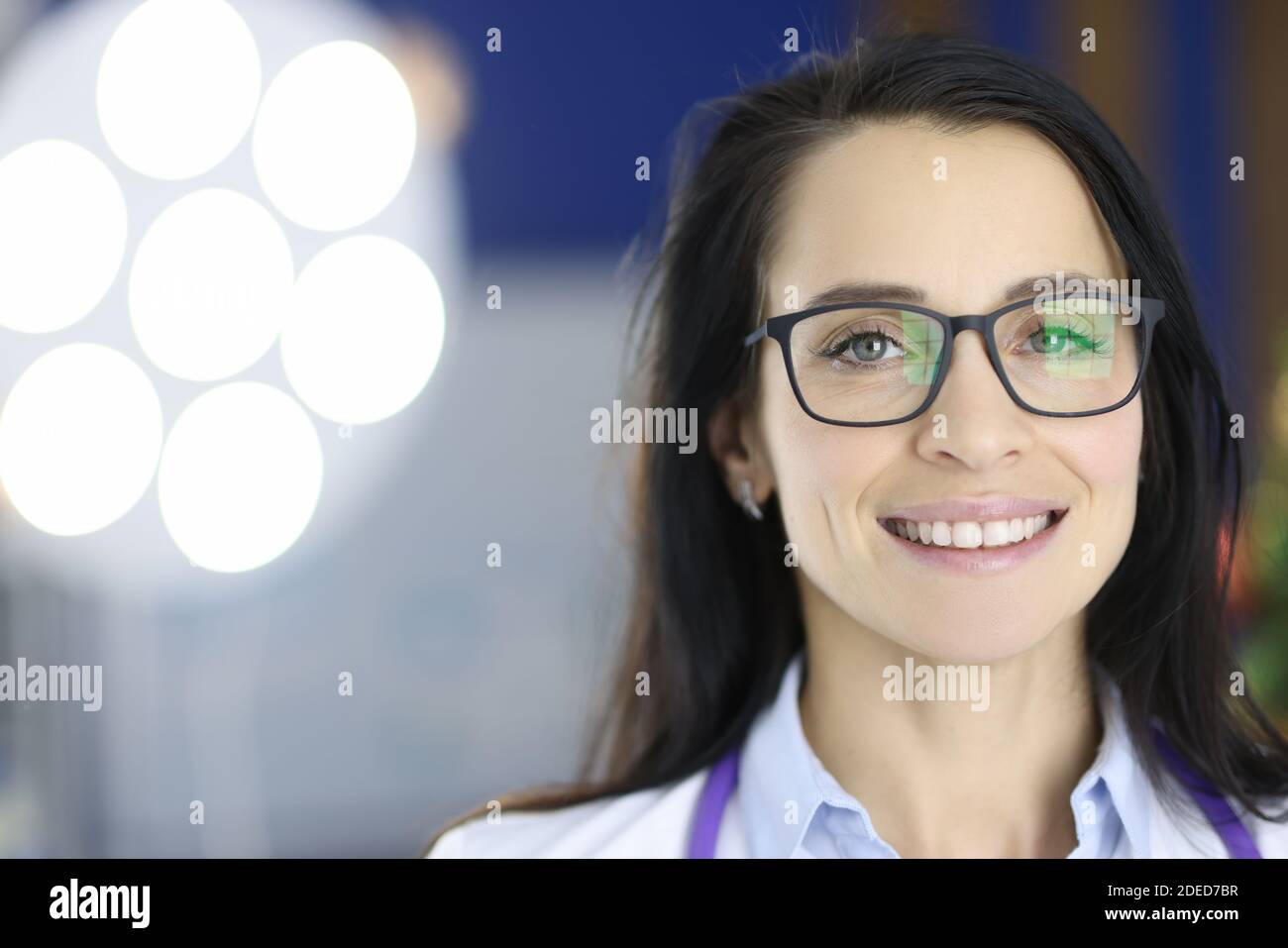Ritratto di sorridente medico con bicchieri in sala operatoria. Foto Stock