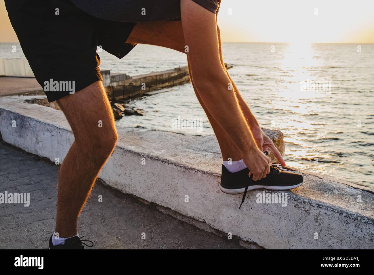 Uomo che si prepara a fare jogging vicino al mare al mattino. Foto Stock