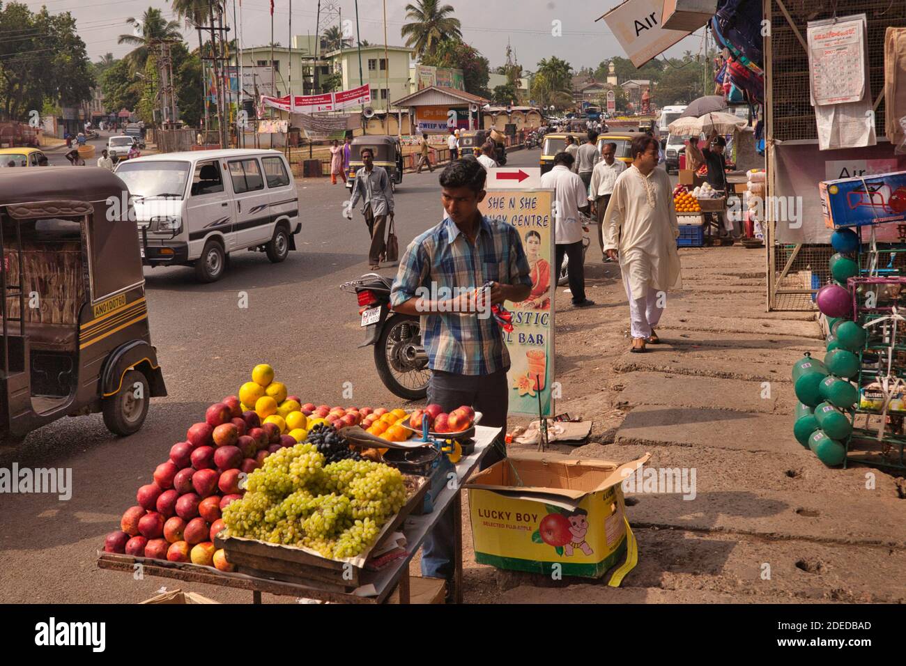 Un venditore di bancarelle di frutta nella strada principale di Port Blair nelle Isole Andamane con traffico e persone che passano da Foto Stock