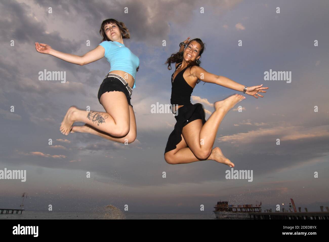 due giovani donne saltano in aria, il cielo come sfondo Foto Stock