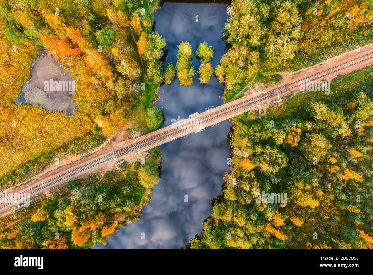 Foresta fiume con riflesso cielo attraversato da ferrovia. Vista dall'alto in colori autunnali Foto Stock