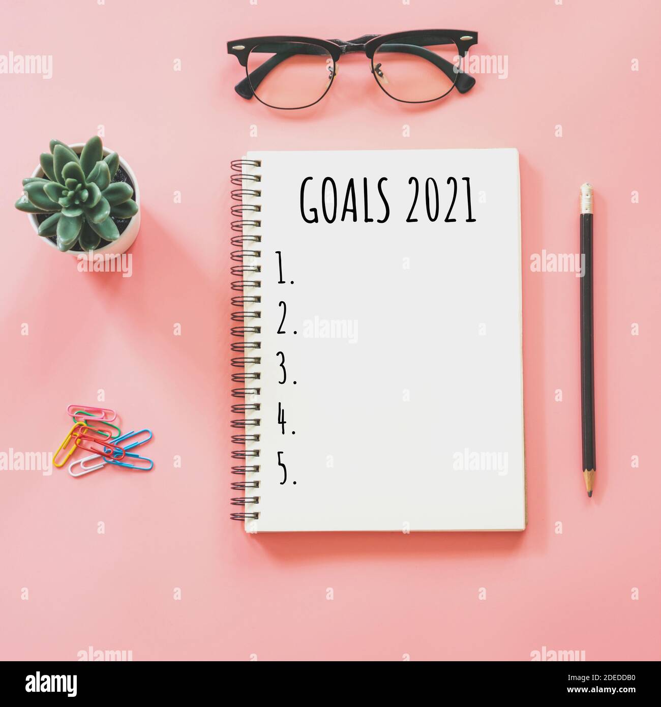 2021 concetto di anno nuovo. Elenco degli obiettivi in blocco note, smartphone, cancelleria in colore rosa pastello con spazio di copia Foto Stock