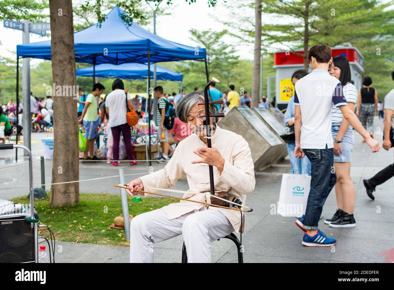 Musicista di strada cinese di mezza età che suona lo strumento musicale cinese tradizionale Erhu (violino cinese) nel Central Park di Shenzhen, Cina Foto Stock