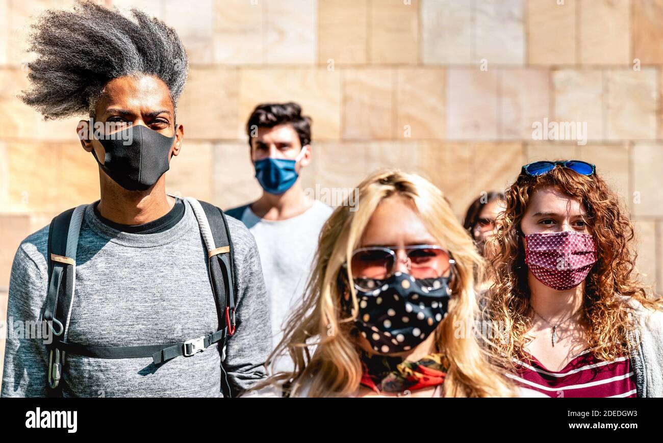 Folla multirazziale che cammina vicino al muro nel contesto urbano della città - Nuovo concetto di stile di vita normale con i giovani coperti da protezione maschera facciale Foto Stock