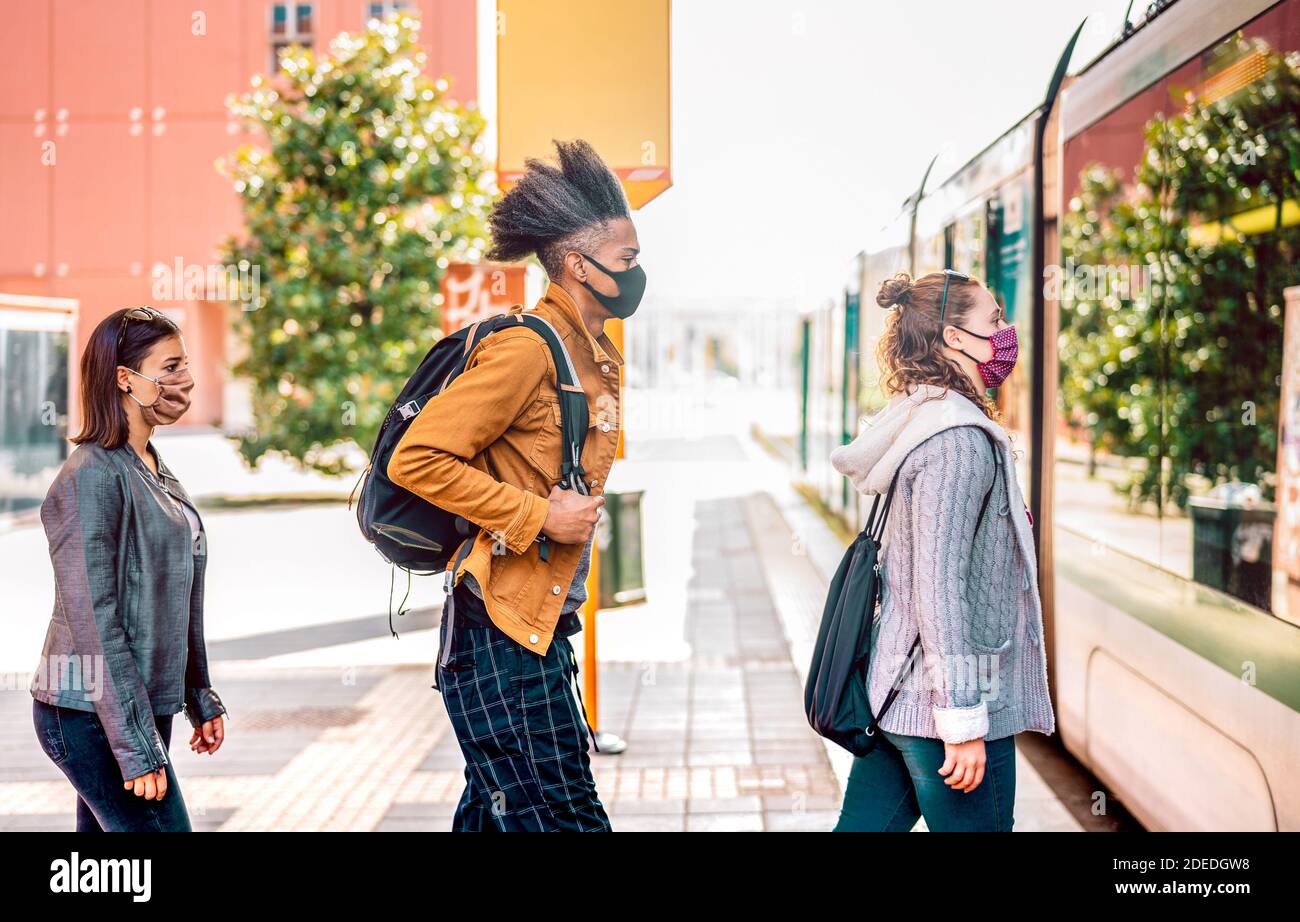 Giovani in attesa in linea che praticano la distanza sociale in autobus Stazione della città - nuovo concetto di trasporto normale con le persone che indossano maschera facciale in coda Foto Stock