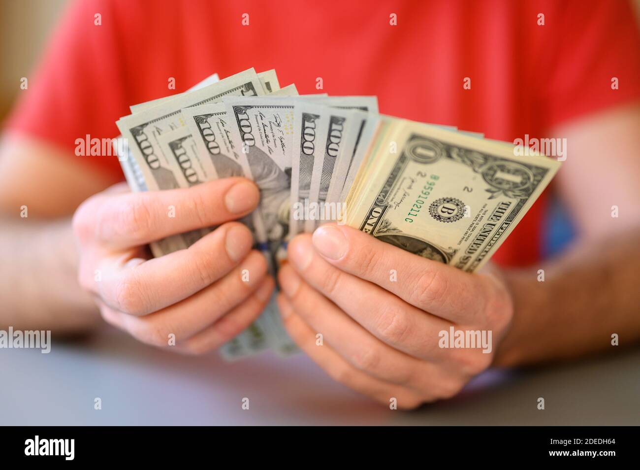 le mani degli uomini tengono e contano 100, 50 e 1 dollaro fatture sulla tabella grigia Foto Stock