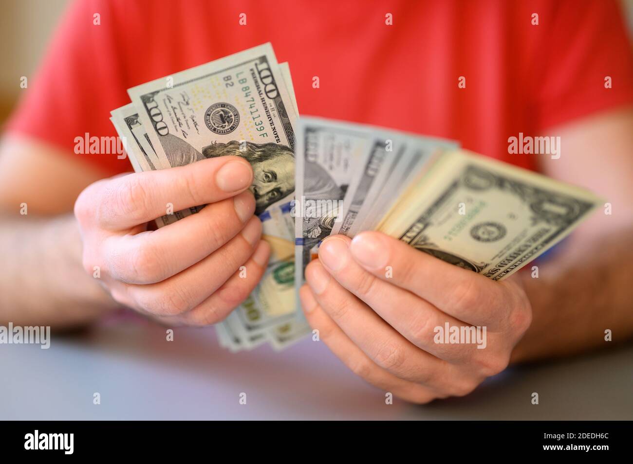 le mani degli uomini tengono e contano 100, 50 e 1 dollaro fatture sulla tabella grigia Foto Stock