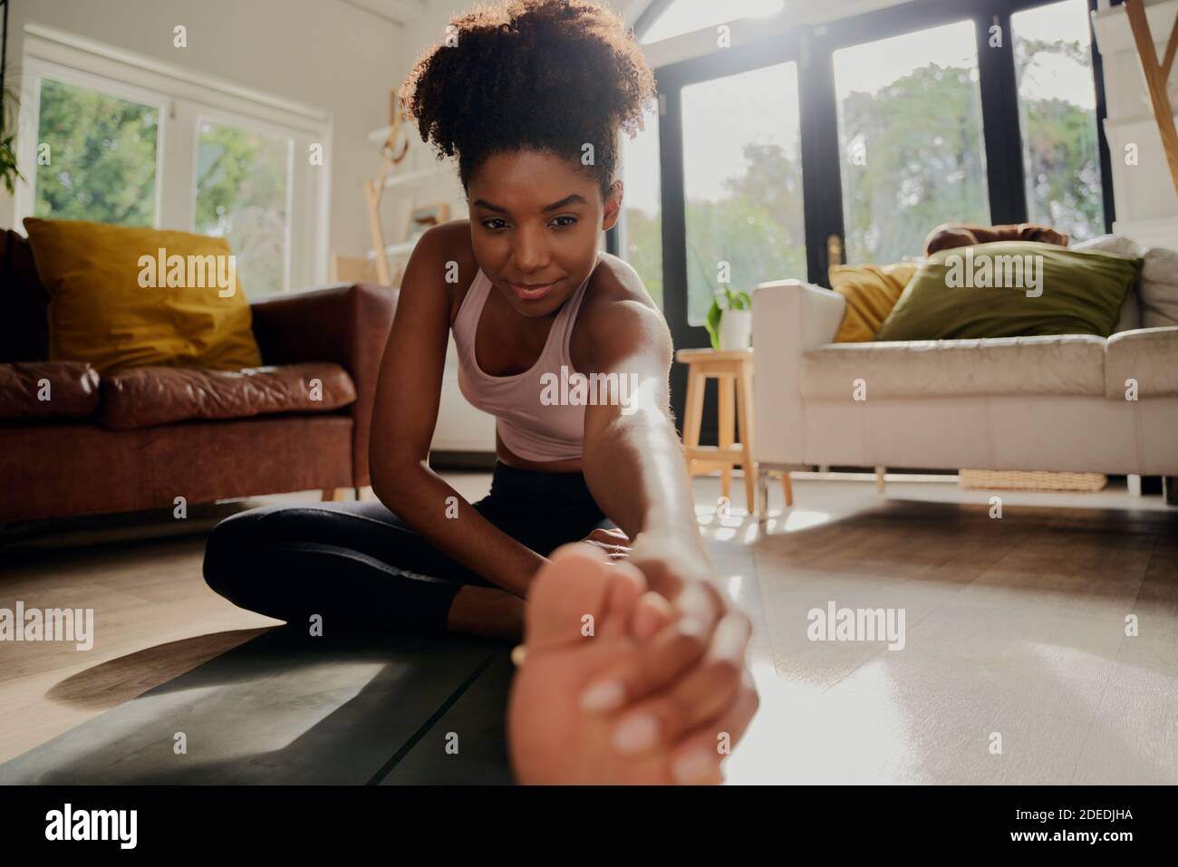 Primo piano ritratto di donna africana che fa esercizio di riscaldamento prima di allenamento a casa Foto Stock