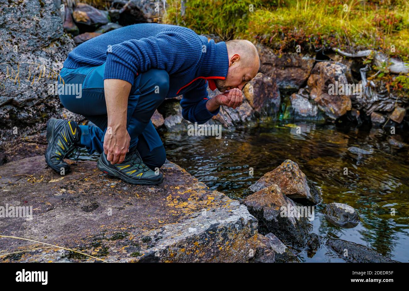Escursionista che beve acqua glaciale pulita da un piccolo ruscello. Primo piano. . Foto di alta qualità Foto Stock