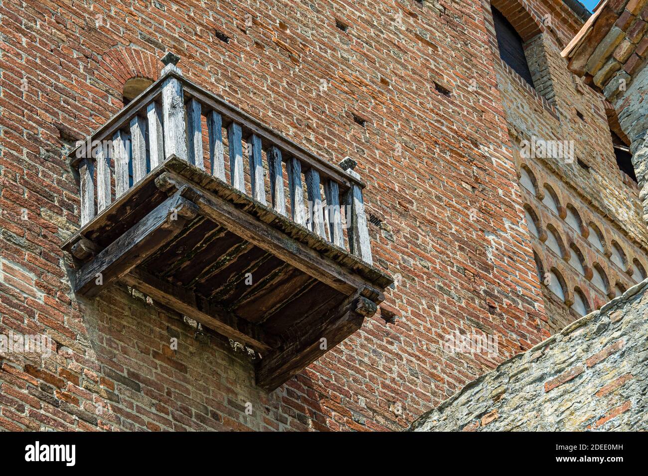 Vista esterna del castello di Serralunga con balcone in legno e case in mattoni - Città di Serralunga, Italia, Piemonte Foto Stock