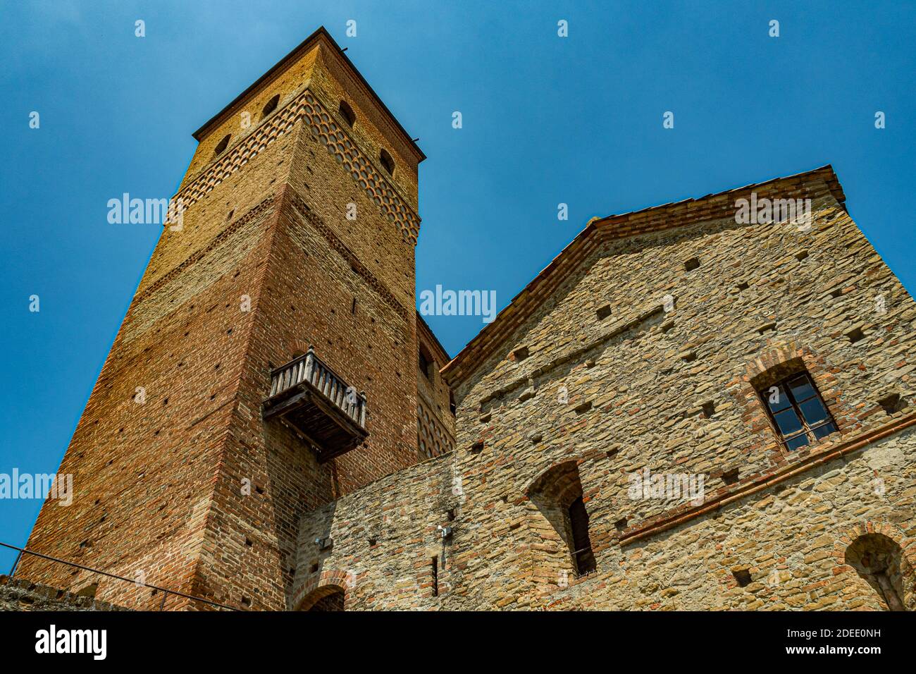 Vista esterna del castello di Serralunga con la torre e le case in mattoni - Città di Serralunga, Italia, Piemonte Foto Stock