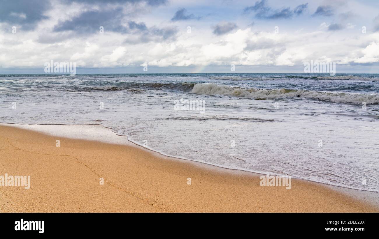 Spiaggia vuota e mare tempestoso in tempo nuvoloso Foto Stock