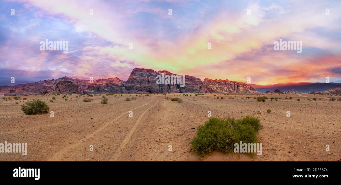 Vista panoramica sul deserto di sabbia rossa con un tramonto dorato nuvoloso a Wadi Rum, Giordania Foto Stock