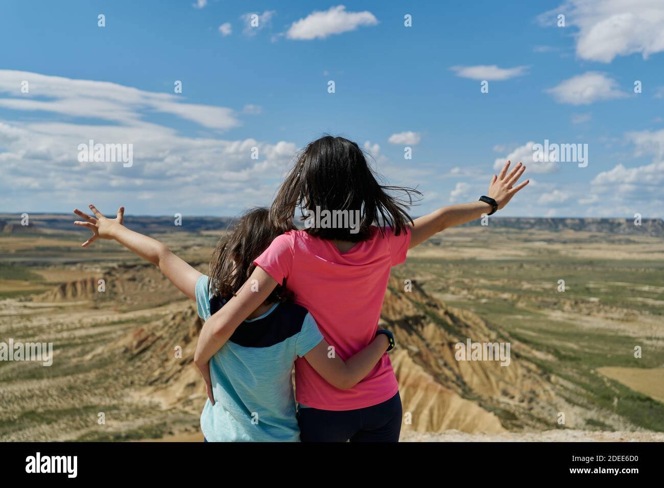 Piccole sorelle in osservazione osservando a braccia aperte una montagna desertica nel parco nazionale di Bardenas Reales a Navarra, Spagna. Concetto di viaggio Foto Stock