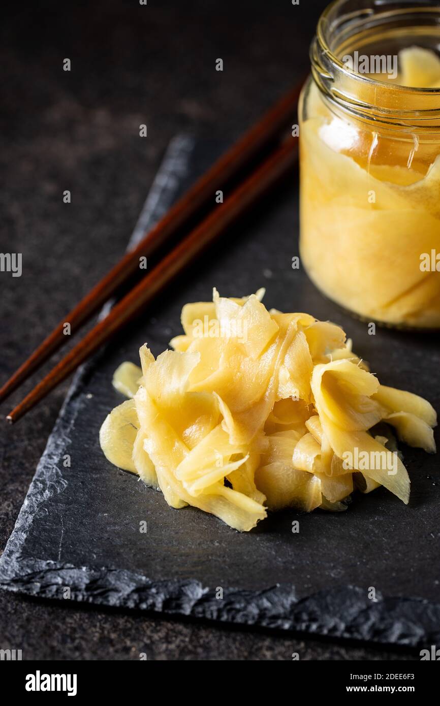 Fette di zenzero di sushi sottaceto su tagliere di pietra nera. Foto Stock