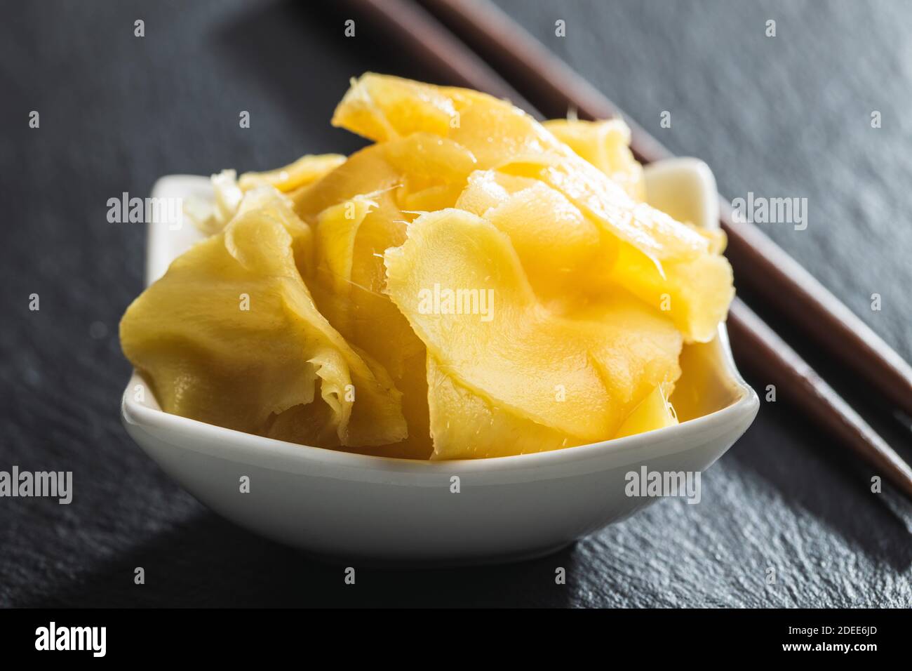 Fette di zenzero di sushi sottaceto in ciotola su tavola nera. Foto Stock