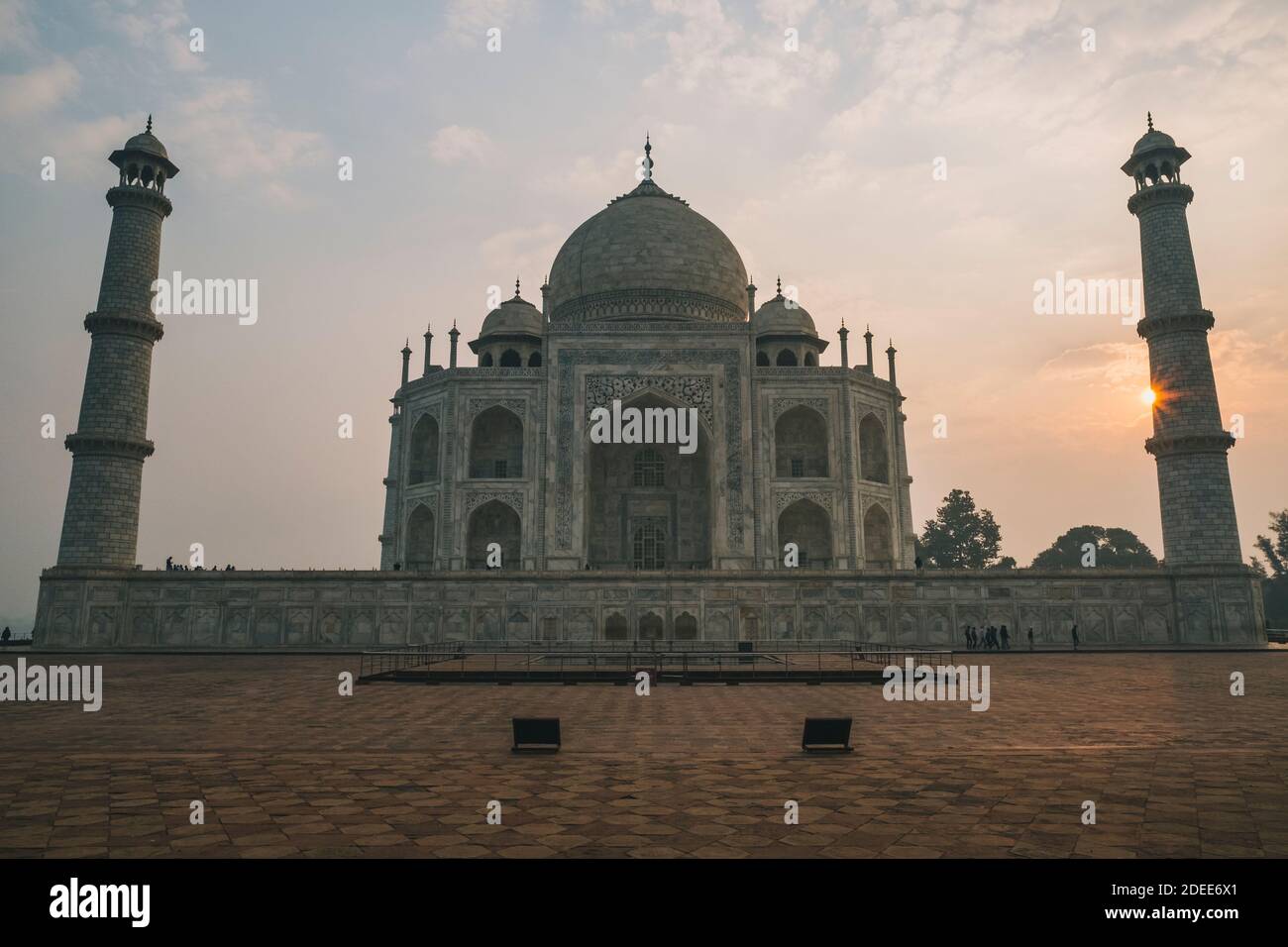 Taj Mahal ovest faccia contro cielo nuvoloso e il sole peaking su uno dei minareti, durante l'alba, Agra, India Foto Stock