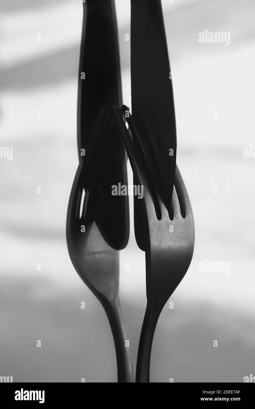 Un'immagine verticale in scala di grigi di coltelli e forche Foto Stock