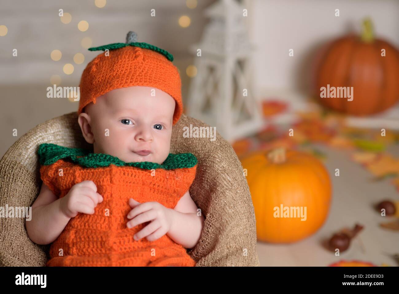 Bambino in tuta di zucca su sfondo bianco con zucca Foto Stock