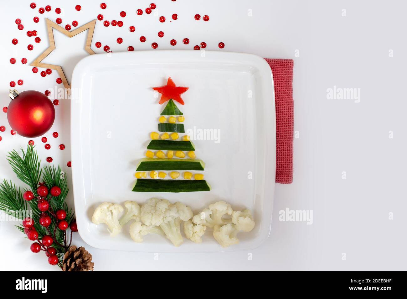 Decorazione del tavolo di Capodanno, cetriolo e insalata di mais sotto forma di albero di Capodanno, su un piatto bianco Foto Stock