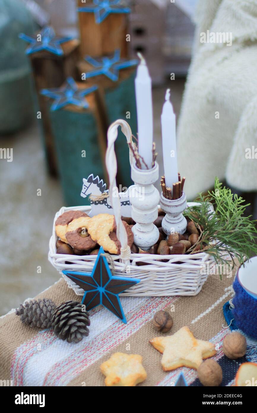 Cesto di vimini bianchi, con biscotti e noci e uno sprig di abete rosso, con candele bianche Foto Stock