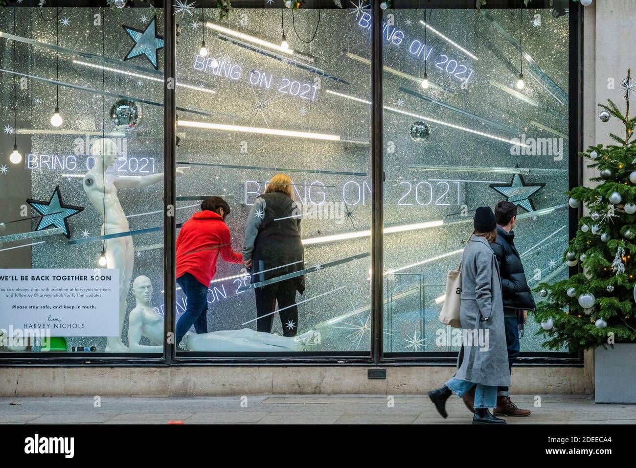 Londra, Regno Unito. 30 novembre 2020. Harvey Nichols effettua regolazioni finali ai suoi messaggi di finestra - Bah Humbug e portare su 2021. I rivenditori chiusi fanno del loro meglio per promuovere le vendite di Natale. La gente è ancora fuori nel centro di londra e si prepara a riaprire quando la seconda chiusura si avvicina alla fine. Le luci di Natale sono accese ma i negozi sono chiusi. Molte persone indossano maschere, anche all'esterno. Credit: Guy Bell/Alamy Live News Foto Stock