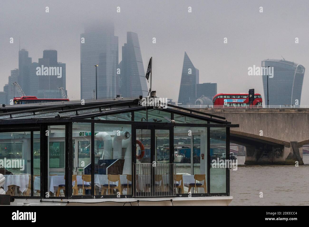 Londra, Regno Unito. 30 novembre 2020. Un ristorante galleggiante Bateau Mouche si trova vuoto come il fiume Tamigi normalmente occupato - la città parzialmente nascosta di Londra fornisce uno sfondo grigio per gli autobus che viaggiano sopra il ponte di Waterloo - molti di questi hanno messaggi realting a Covid 19. In una mattinata misteriosa, una certa vita continua a Londra quando il secondo Coronavirus Lockdown si avvicina al suo End Credit: Guy Bell/Alamy Live News Foto Stock