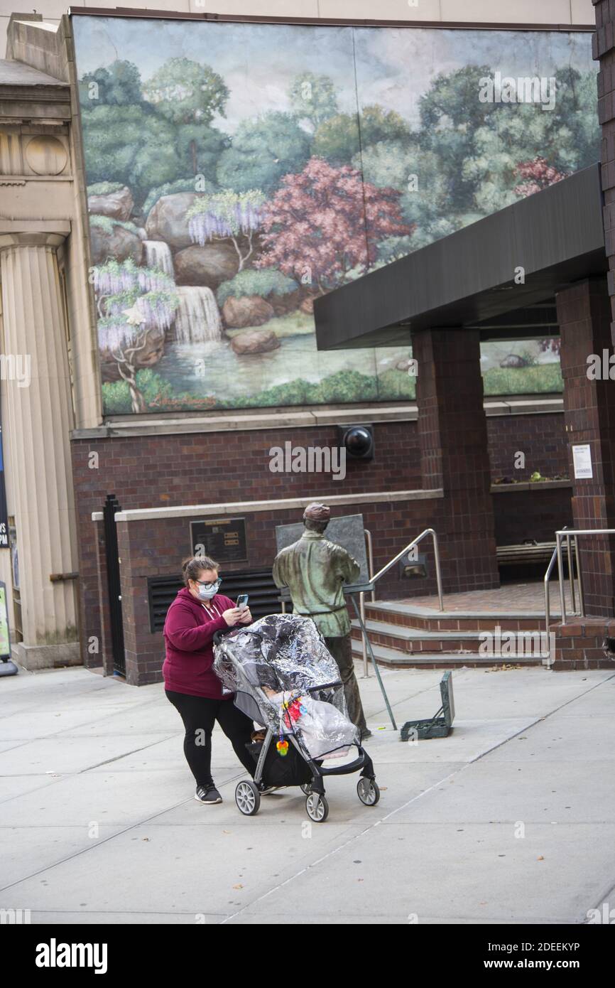 Donna con il carrello del bambino si ferma vicino alla luce destra 'sculpture da J. Seward Johnson Jr. Di fronte al muro di pittura da Lillian Kennedy sulla 34a Est Stree Foto Stock