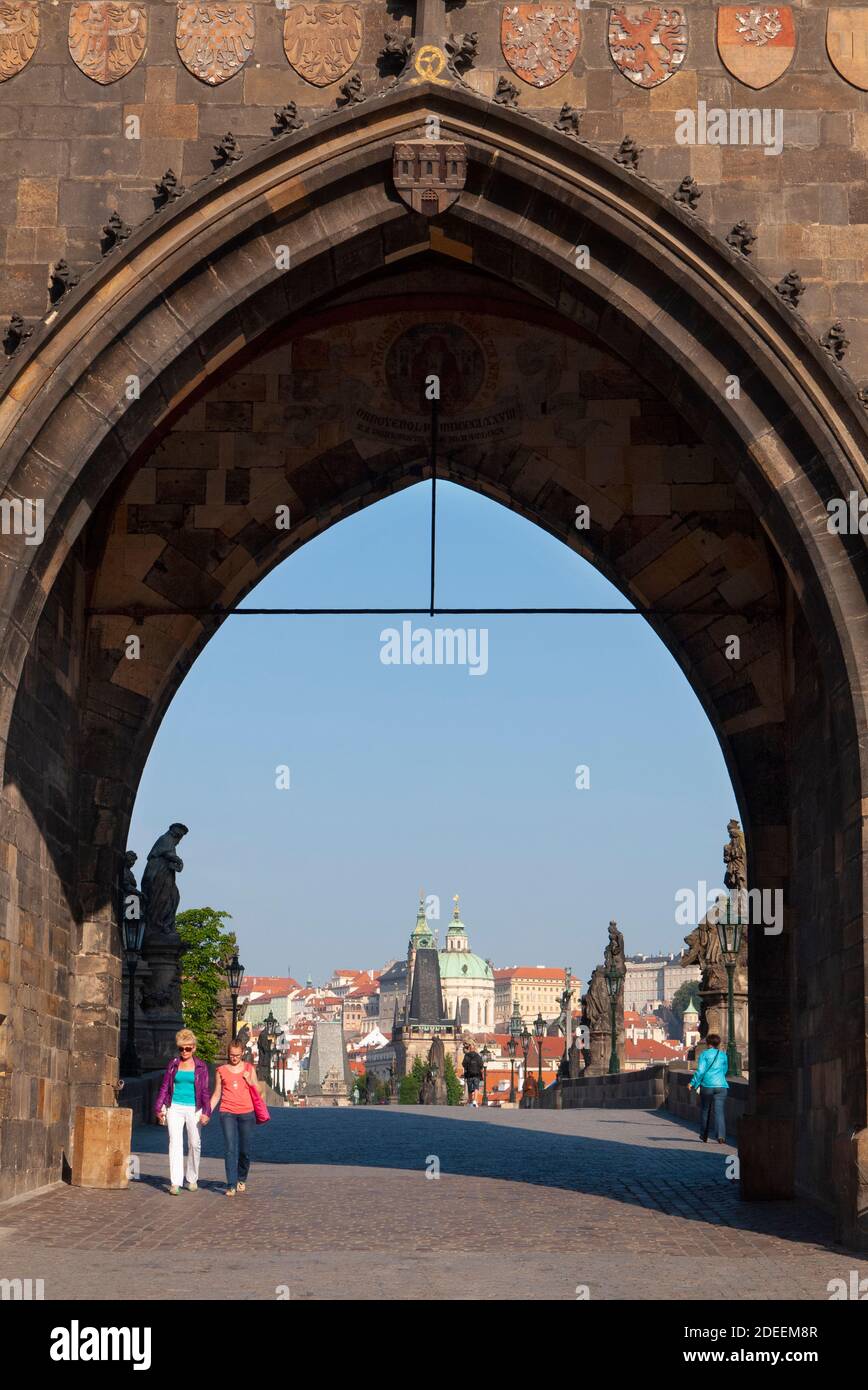 Una coppia cammina attraverso la porta della Torre del Ponte della Citta' Vecchia all'estremità orientale del Ponte Carlo sul Fiume Moldava, Praga, capitale della Repubblica Ceca Foto Stock