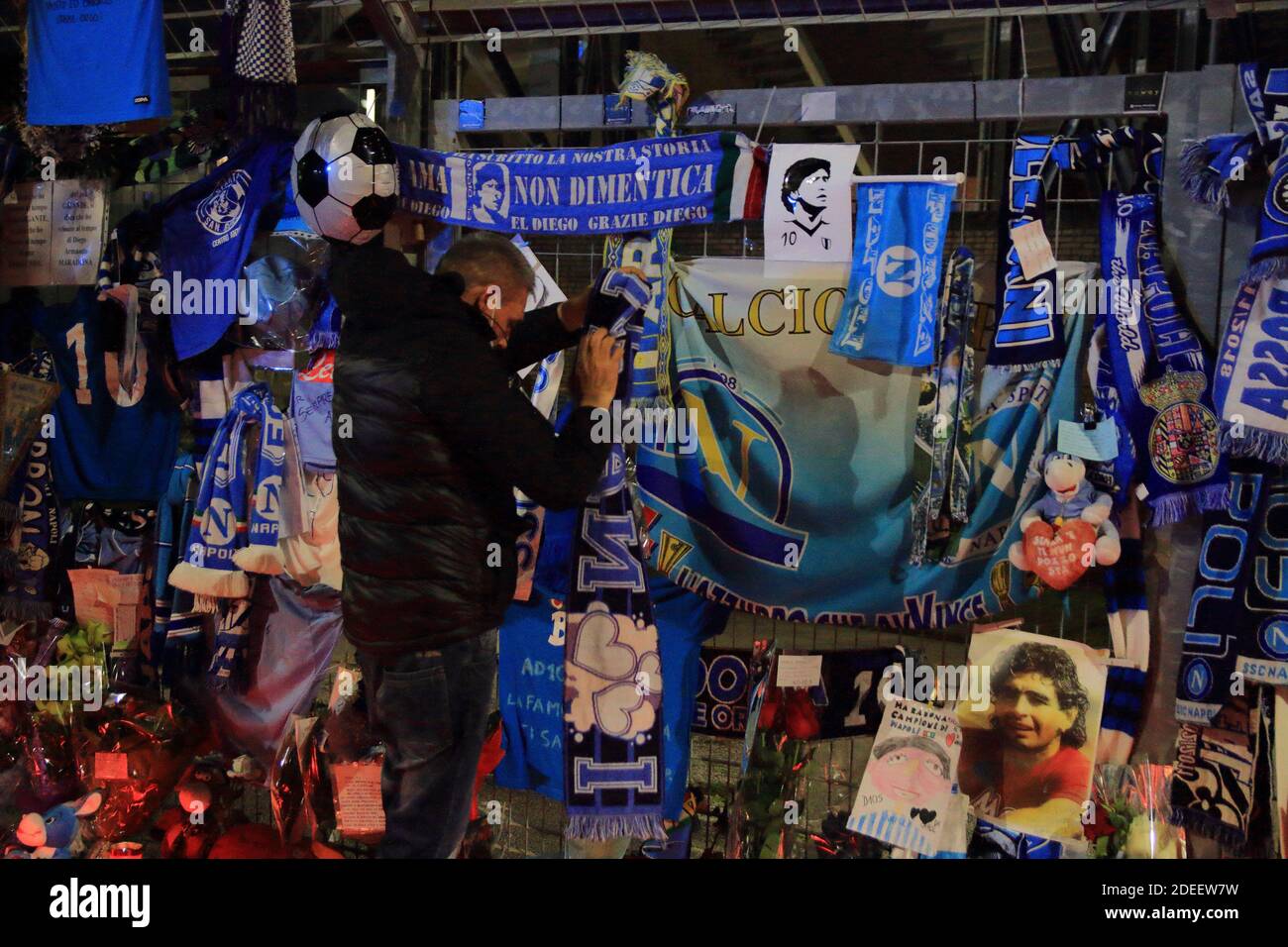 Un fan mette una sciarpa di Napoli in memoria di Diego Armando Maradona davanti alle porte dello Stadio San Paolo , nei giorni successivi alla morte Foto Stock