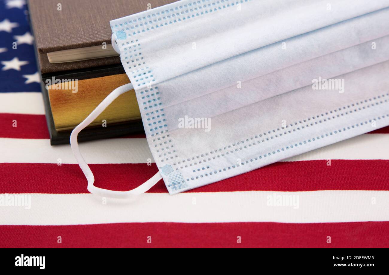 Maschera di protezione virale con libri sulla bandiera americana riflettono la scuola regole per proteggere contro la diffusione del coronavirus in tutta la nazione Foto Stock