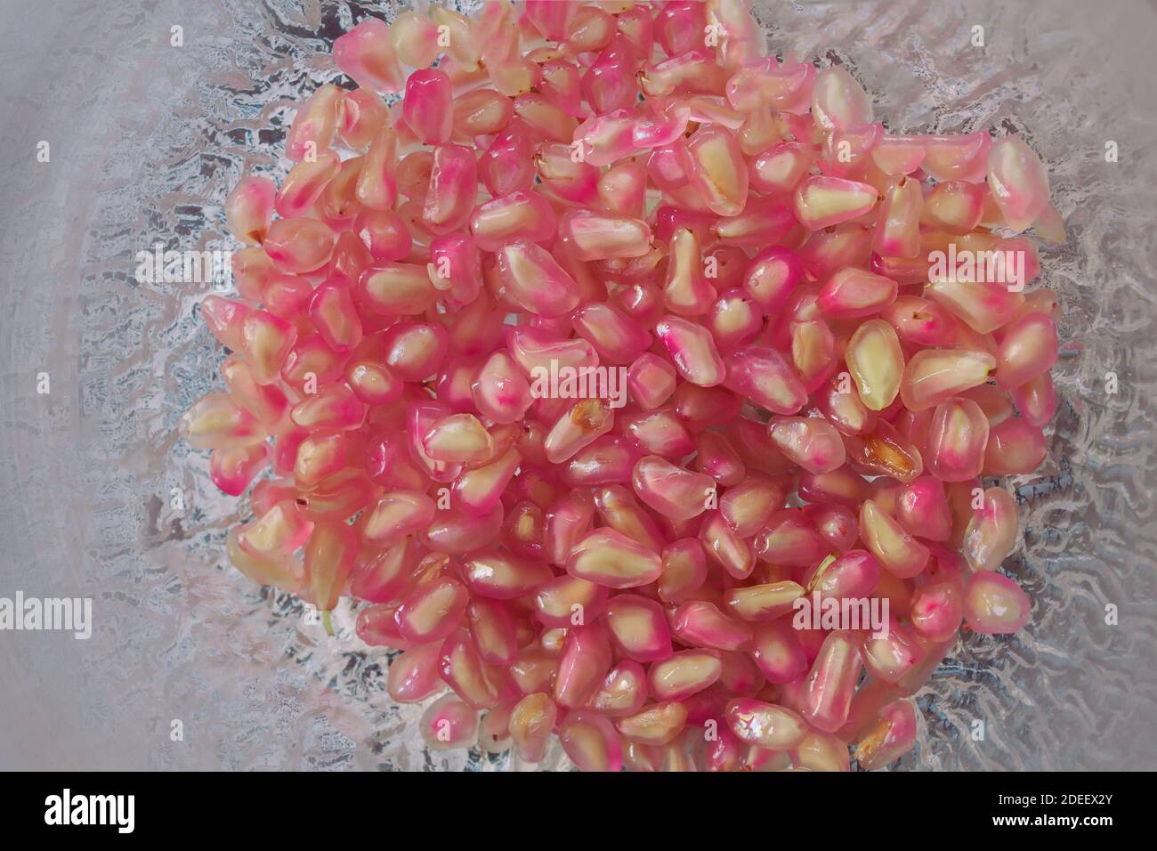 Un sacco di semi di melograno in un elegante recipiente di vetro mobile. Cibo naturale e sano. Foto Stock