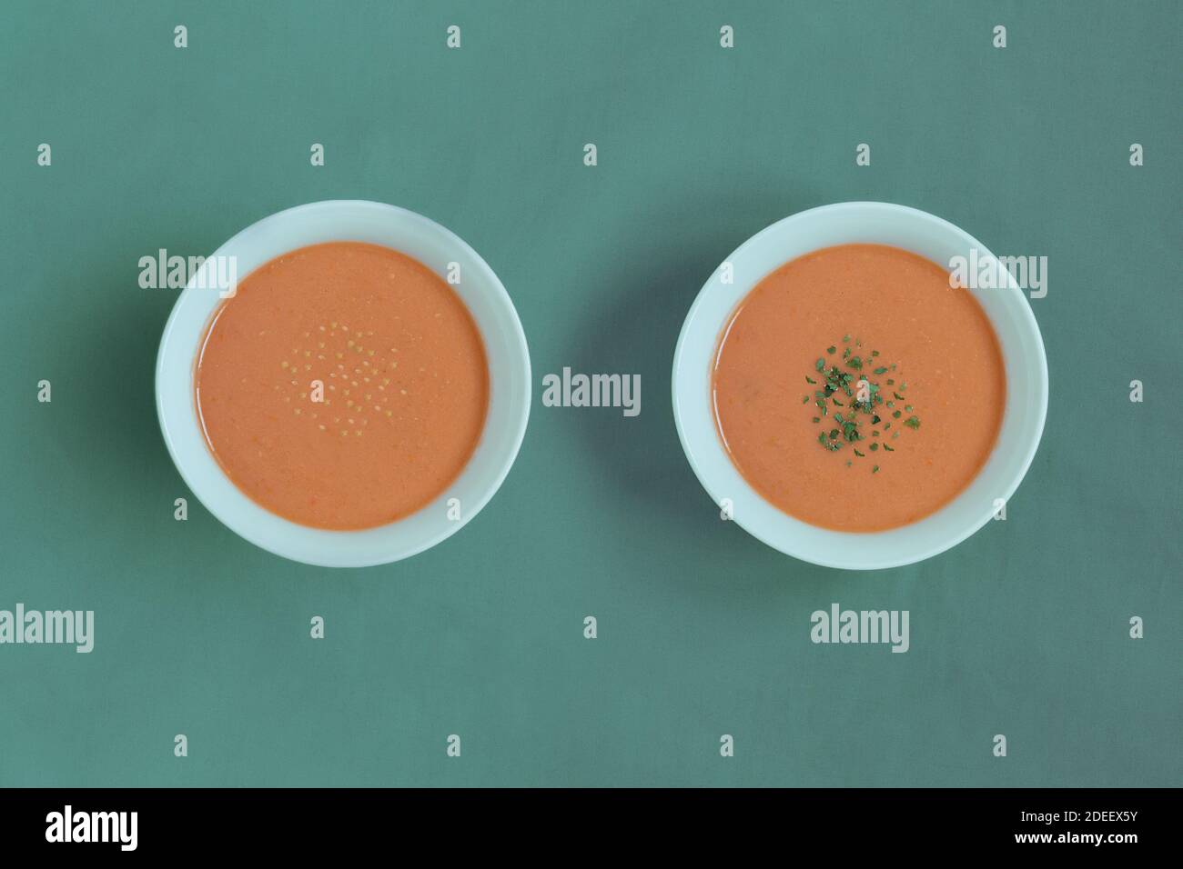 Due eleganti ciotole rotonde con specie diverse su una tovaglia verde. Colorato piatto tipico spagnolo di zuppa fredda di verdure crude schiacciate. Foto Stock