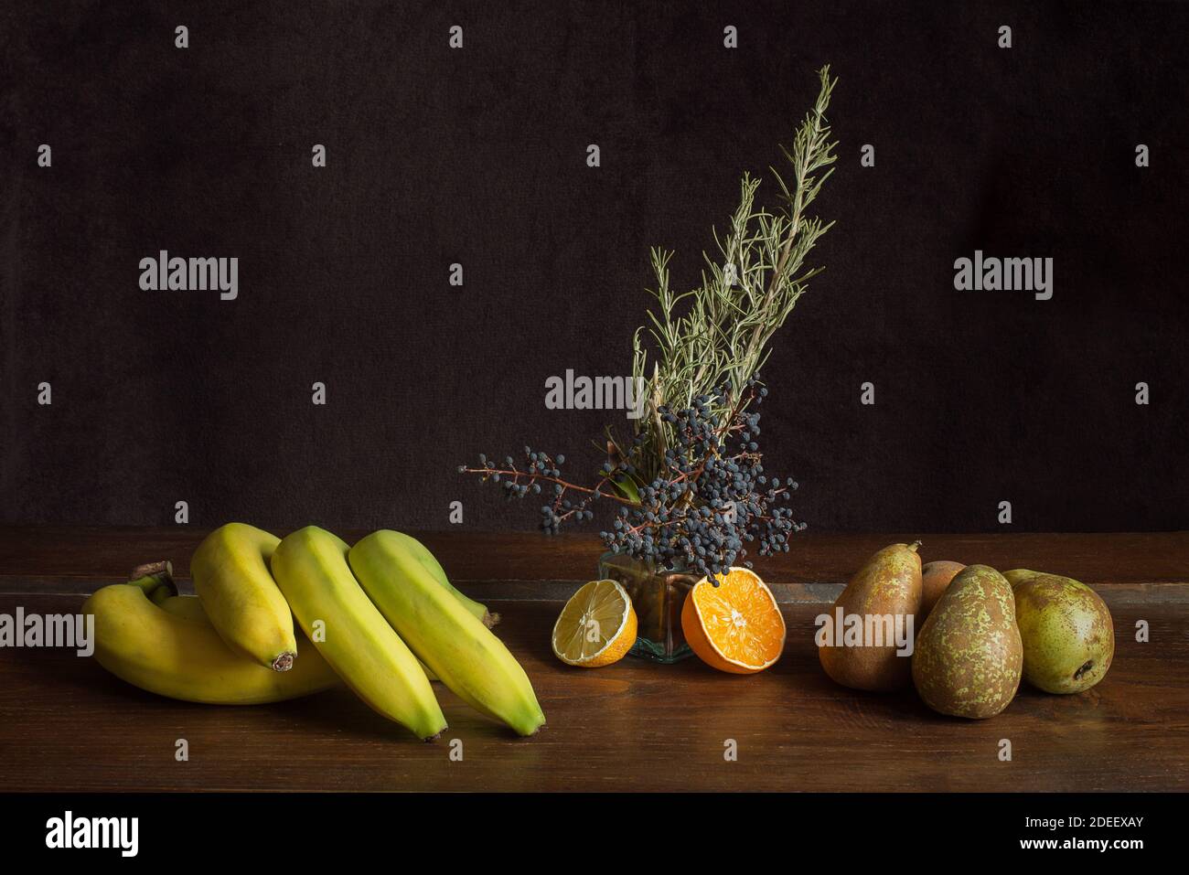 Ancora vita con banane e pere e vetro trasparente con semi di mela nespola e crema con rami privati con more e rosmarino fresco. Foto Stock