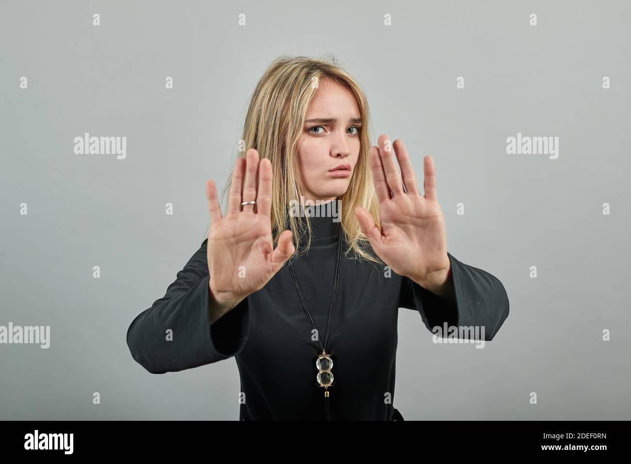 Palm braccio sollevato aria arrabbiato guardare dritto non si passa attraverso l'espressione facciale duro. L'aspetto serio richiede l'arresto, tira la fotocamera in avanti, dice no, disaccosisce, si acciglia viso, avviso Foto Stock