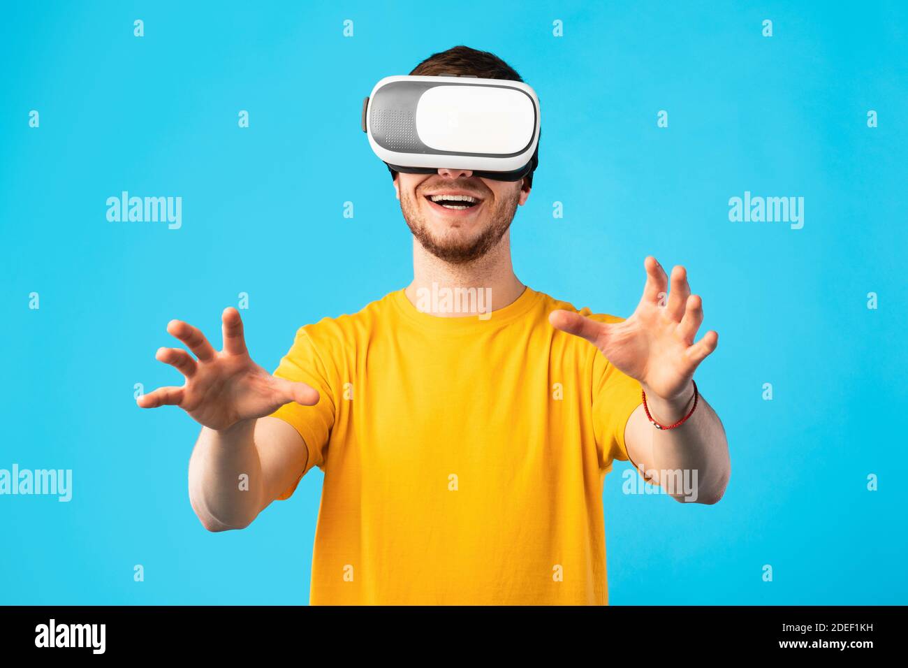 Uomo sorridente che indossa cuffie per la realtà virtuale in studio Foto Stock