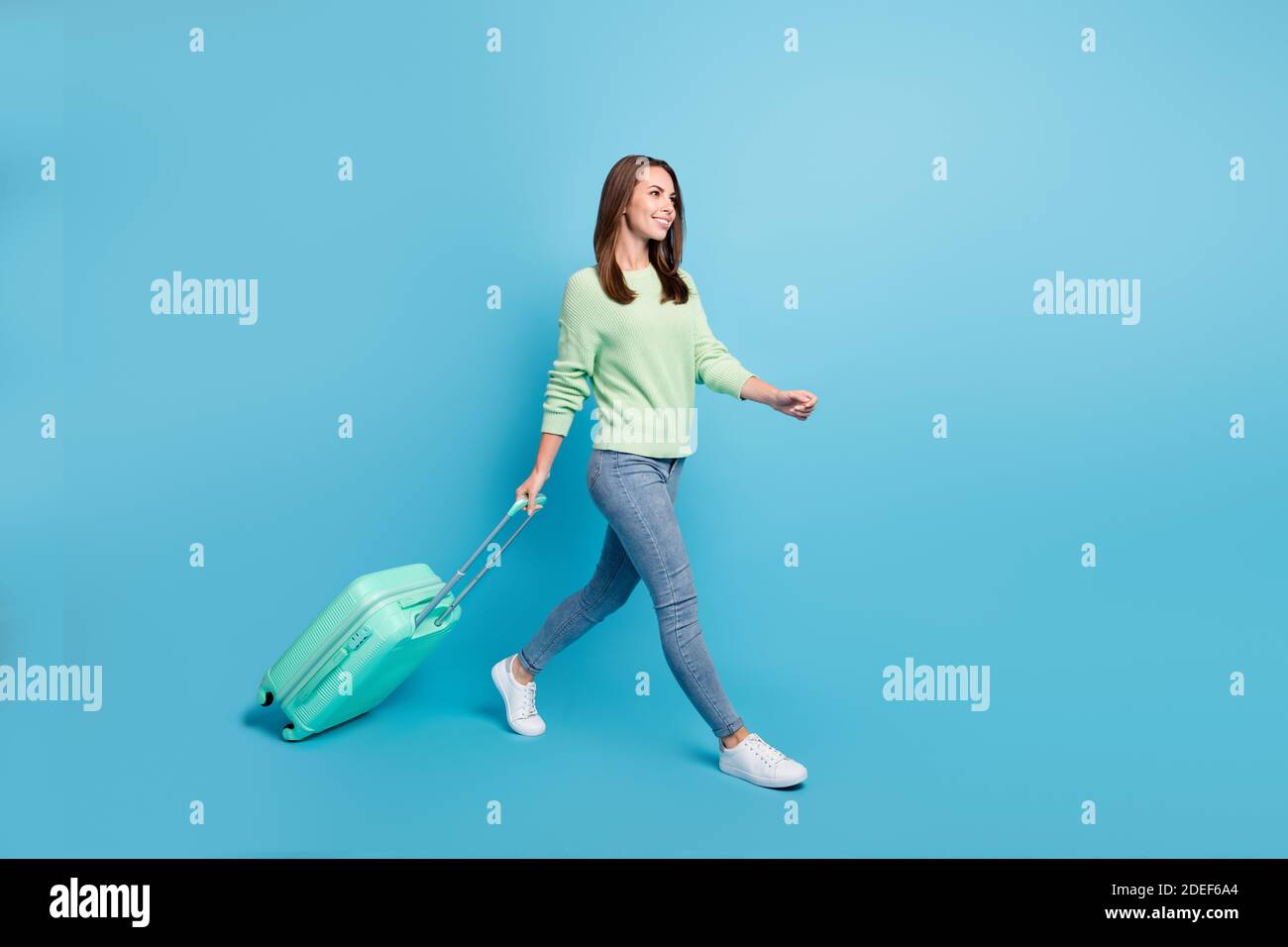 Ritratto fotografico di soddisfatta bella ragazza andando a viaggiare mantenere valigia che si fa sorridere isolato su uno sfondo di colore blu brillante Foto Stock