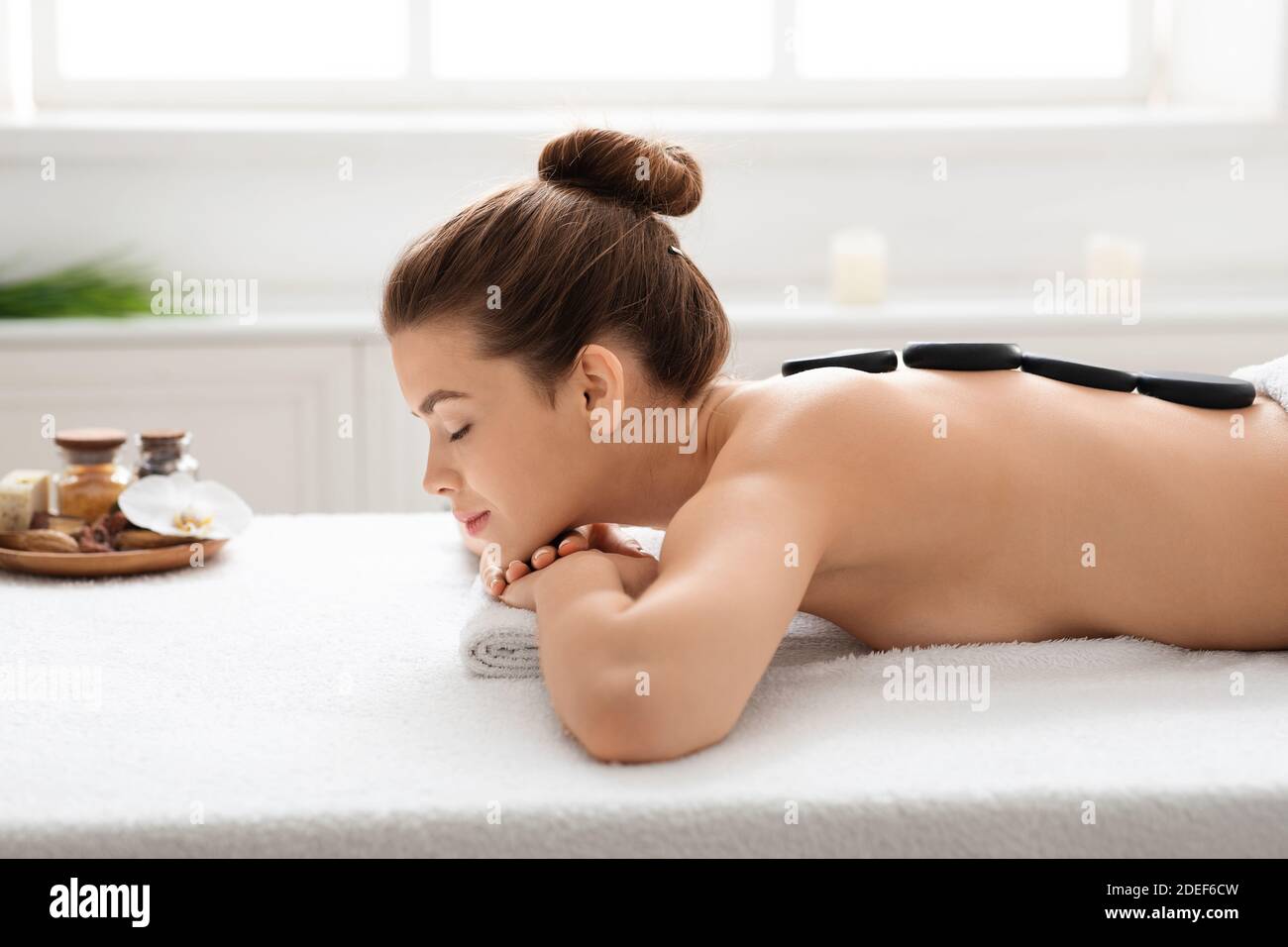 Vista laterale della giovane donna che riceve massaggio in pietra calda Foto Stock