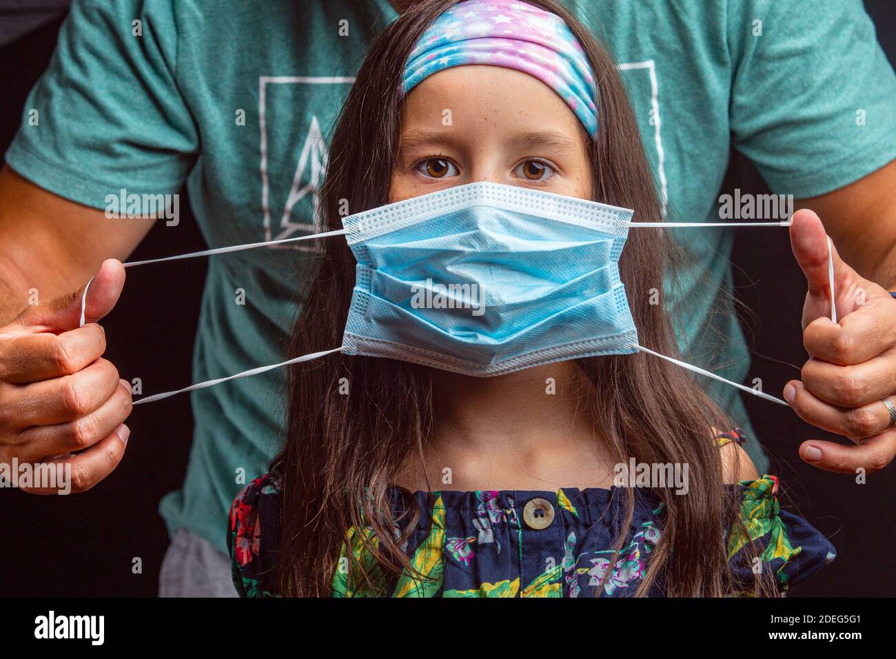 Il genitore mette una maschera sul viso del bambino. Foto Stock