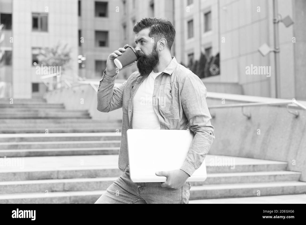 Pausa caffè. Ragazzo che va a lavorare sullo sfondo urbano. Uomo con computer portatile a piedi strada vuota. Vita di affari. Vita moderna. Hipster lavoratore moderno con notebook. Tecnologia moderna. Era delle distanze sociali. Foto Stock