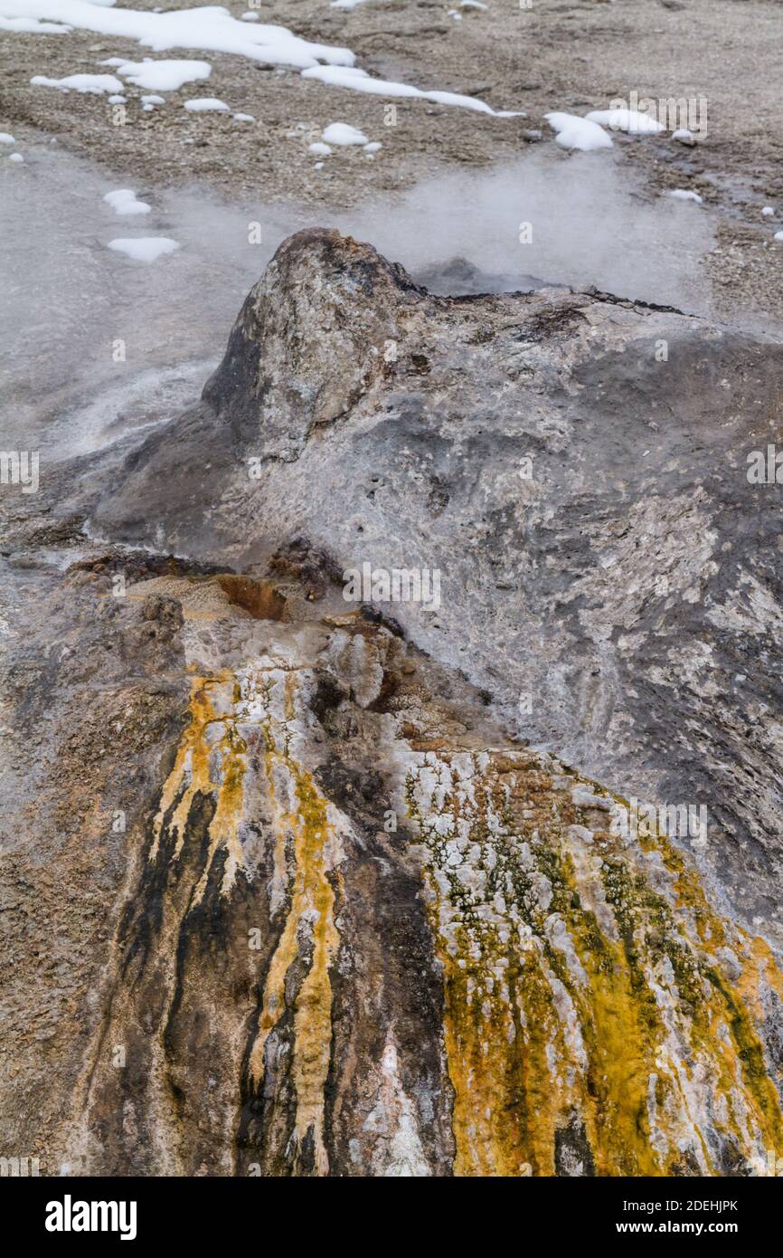 L'acqua calda della sorgente termale Chimney Cone scorre sopra Tappetini microbici termofili colorati sulla strada verso il Firehole Fiume a Yellowstone National Foto Stock